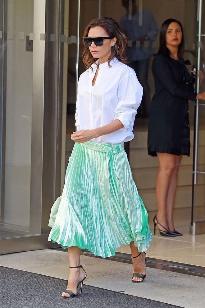 The ever-polished Victoria Beckham wears a crisp white shirt with a green pleated velvet skirt and open toe heels. Photo: Getty