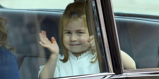 Three-year-old Princess Charlotte, who is serving as a bridesmaid in the wedding, waves to the crowds from the backseat of the car.