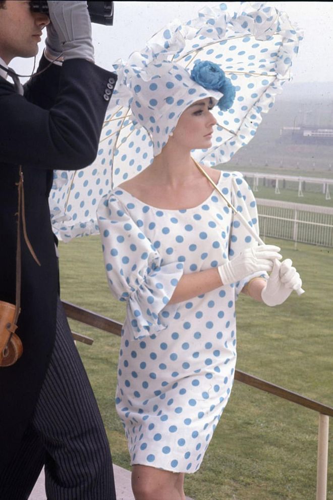 A woman poses with polk-a-dot parasol and matching ascot dress while watching a race. Photo: Getty 