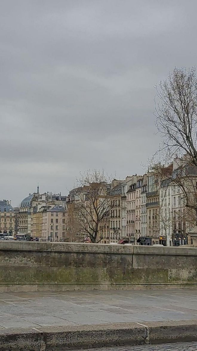 The Seine river runs through the heart of Pairs, iconic Haussmannian apartment facades lining its banks.