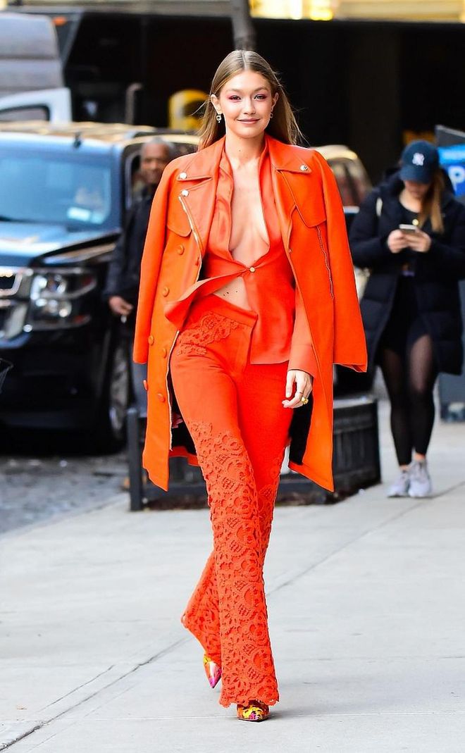 The Queen of Monochrome dressing is back with a vibrant orange outfit by Ronald van der Kemp. She paired the look with Christian Louboutin's Loubigraf booties. 