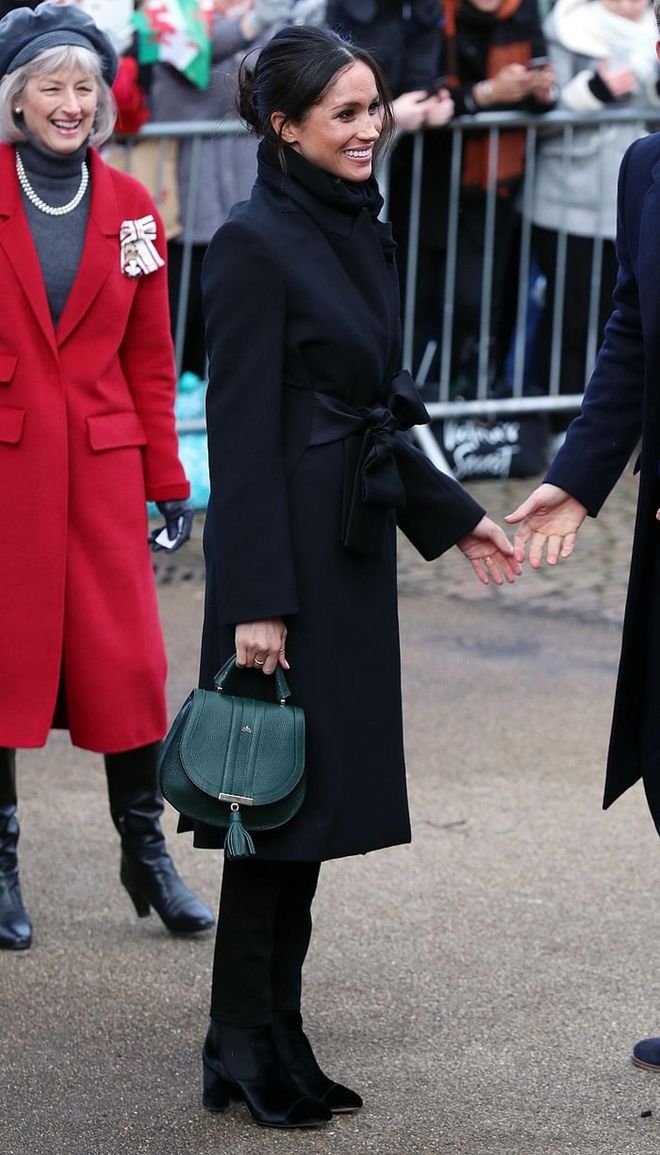 Meghan showed up for her third official event as a couple in a Stella McCartney black wrap trench coat and  Demellier London's Mini Venice in a deep forest green. Photo: Getty 