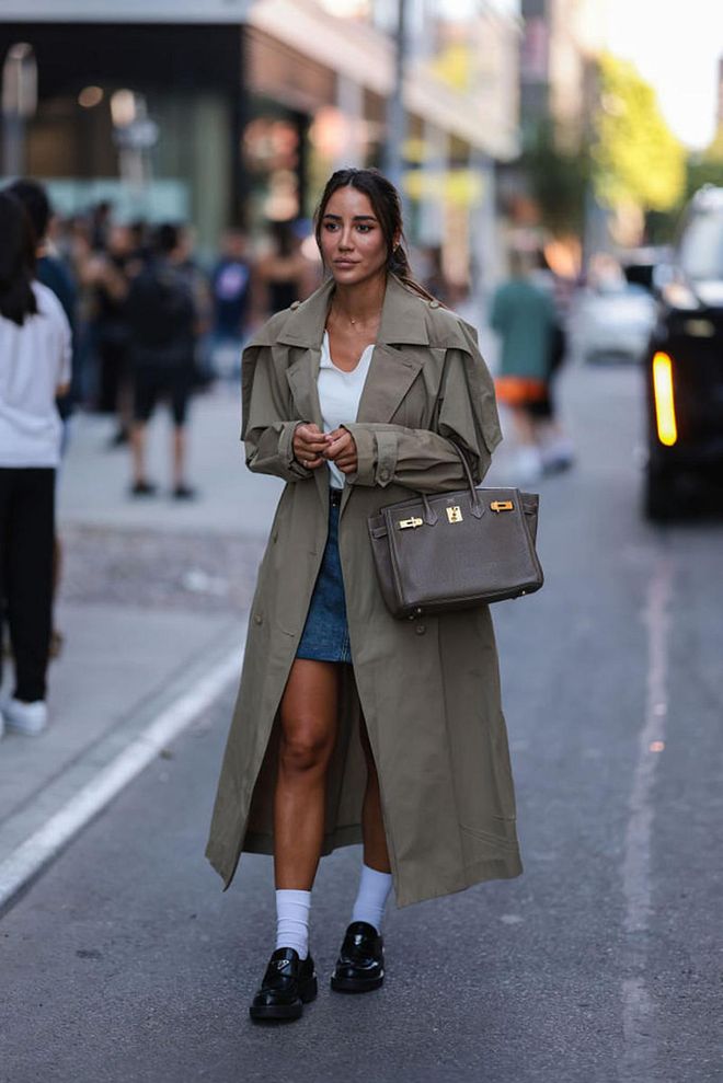 NEW YORK, NEW YORK - SEPTEMBER 10: Tamara Kalinic seen wearing black sunglasses, diamonds earrings, a gold chain necklace, a white top, a beige long trench coat, a blue denim short skirt, a gray taupe Birkin handbag Hermes, white socks, black shiny leather loafers from Prada, outside Tibi , during New Yorker Fashion Week, on September 10, 2022 in New York City. (Photo by Jeremy Moeller/Getty Images)