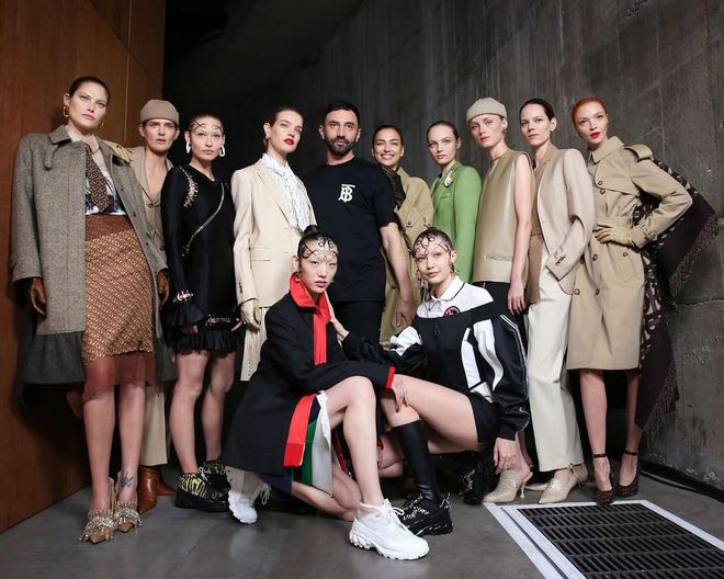 As he did for his expansive debut, Riccardo Tisci once again presented
more than a hundred looks covering every facet of Britishness—from the club kids to the country-house set. However,
this time around, he flipped the order, showing the street-oriented looks of the bright young things first, before segueing into everything prim, posh and beige.
The set of the presentation reflected this duality, with half the audience seated in a Brutalist concrete section and the other half ensconced in honey-hued wood.
The first part of the show saw a riff on the uniforms of London subcultures in decades past—’90s tracksuits, raver brights, puffer jackets and bootleg Burberry checks, glammed up by crystals,
corsets and lacy little slips. For the sophisticates, Tisci proposed neat skirt suits in warm shades of camel and chocolate worn under classic Burberry trenches; the clean lines occasionally broken by ladylike pleats and handkerchief hems.