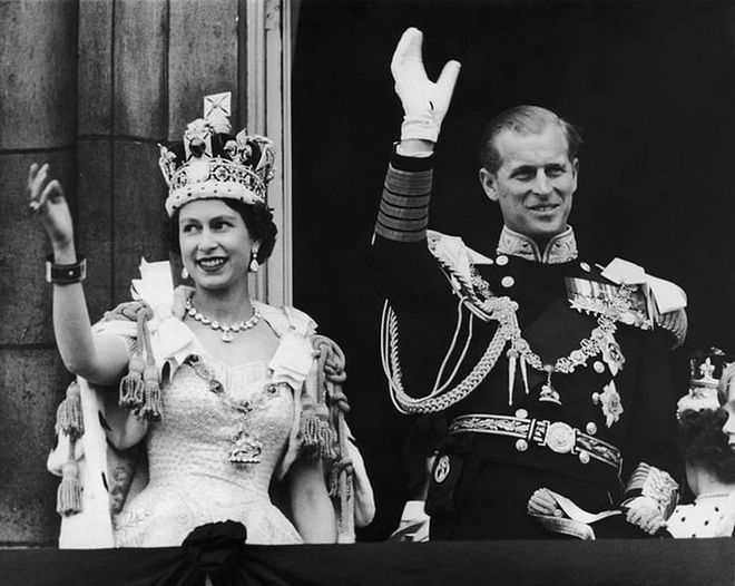 Queen Elizabeth II and the Duke of Edinburgh wave at the crowds from the balcony during her Coronation at Buckingham Palace.