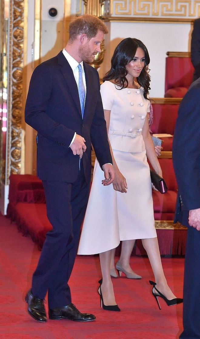 The Duchess of Sussex attends the Queen's Young Leaders Awards Ceremony in a custom beige Prada two-piece with a double-breasted button front. Her She paired it simply with black Aquazurra 'Deneuve' Bow Pumps and a Prada Biblioteque Saffiano Leather Chain Clutch.