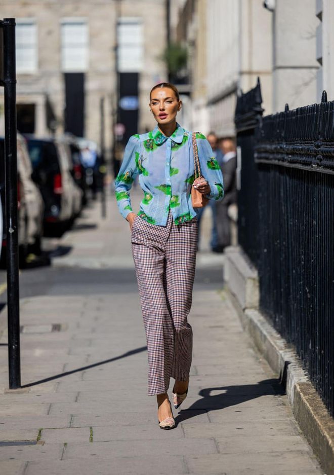 LONDON, ENGLAND - SEPTEMBER 17: Alina Baikova wears checkered pants, blue green blouse with print, Chanel bag outside Paul & Joe during London Fashion Week September 2022 on September 17, 2022 in London, England. (Photo by Christian Vierig/Getty Images)