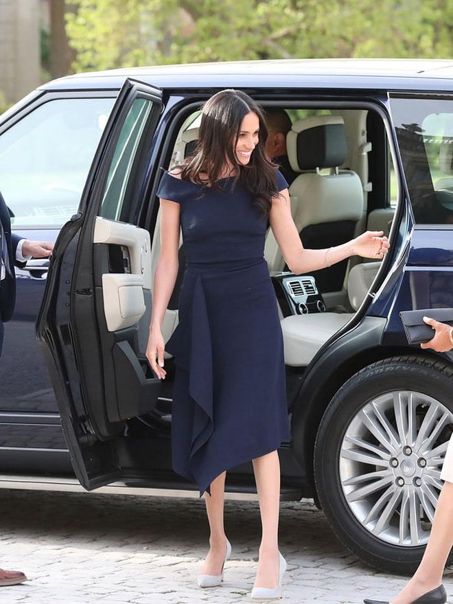 Meghan wore a navy, slightly off-shoulder 'Barwick' dress by Roland Mouret and light grey Manolo suede pumps on the eve of her wedding day. 