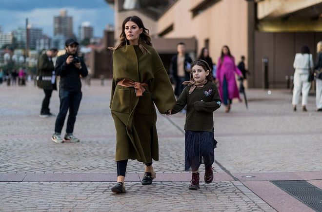 A mother with her child wearing a green wool coat with belt outside Dion Lee. Photo: Getty 
