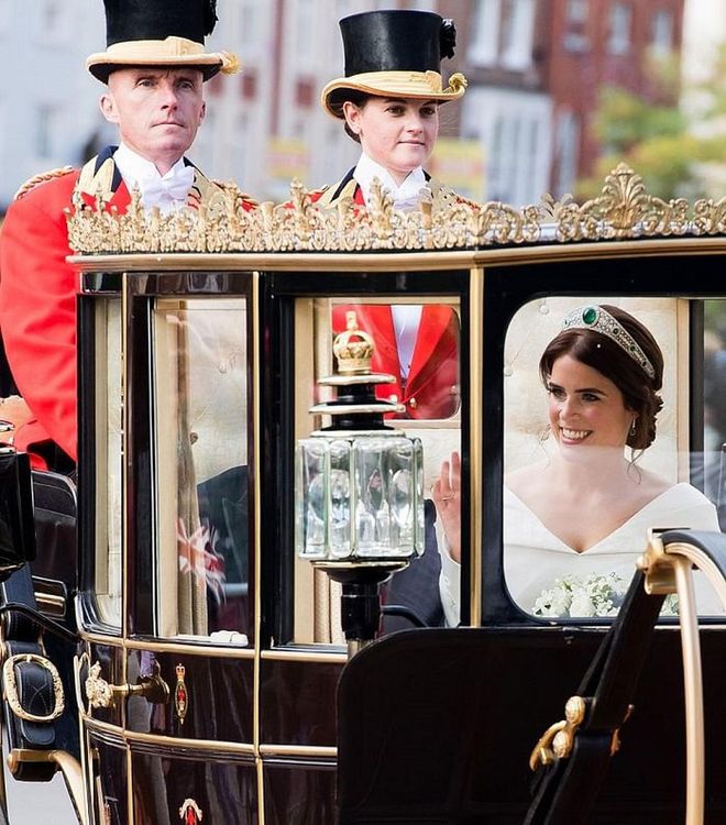 Princess Eugenie waves to the crowds as she rides in horse drawn carriage.