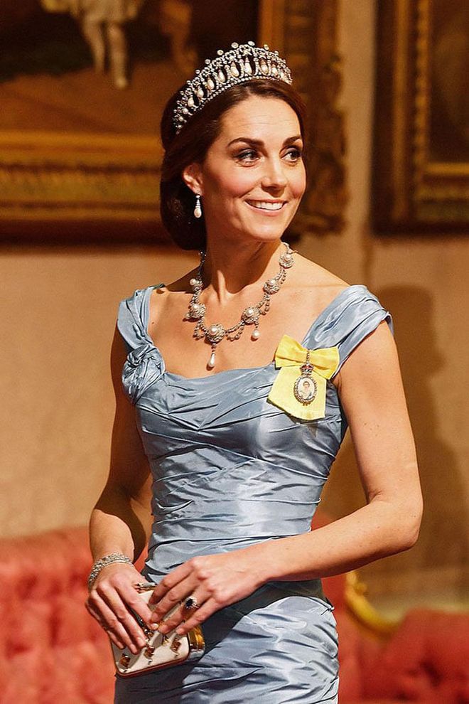 As the Duchess of Cambridge attended a state dinner at Buckingham Palace, all eyes were on her stunning ensemble: an Alexander McQueen gown, the famous Lover's Knot tiara, and a diamond and pearl necklace first owned by Queen Alexandra in 1863. However, the most important part of her regal look was what was pinned to her dress: the Royal Family Order of Queen Elizabeth II. Featuring a portrait of the Queen surrounded in diamonds and pinned to a yellow ribbon, the honor is given by the Queen to members of the royal family as a reward for their service.