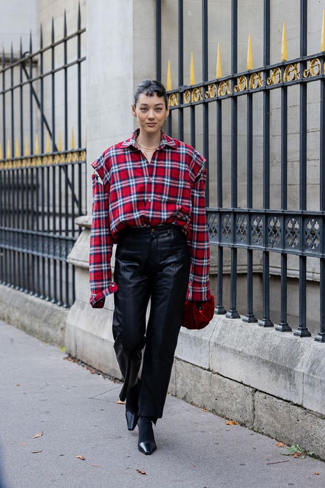 PARIS, FRANCE - SEPTEMBER 28: Kim Jones wears red checkered ripped oversized red white button shirt, black leather pants, ankle boots with heel, red bag outside Undercover during Paris Fashion Week - Womenswear Spring/Summer 2023 : Day Three on September 28, 2022 in Paris, France. (Photo by Christian Vierig/Getty Images)