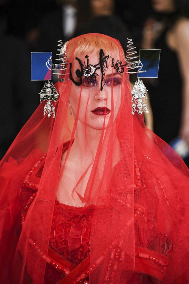 Complementing Perry's dramatic embroidered red veil with are va-va-voom red glitter lips and eyes swept with sparkly blue eye shadow that she wore beneath (Photo: Getty)