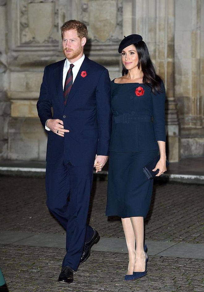 Meghan changed into an outfit featuring her favored bateau neckline for the evening service. Per Meghan's Mirror, the navy peplum top features buttons, and belt detailing, and is paired with a matching skirt. 
