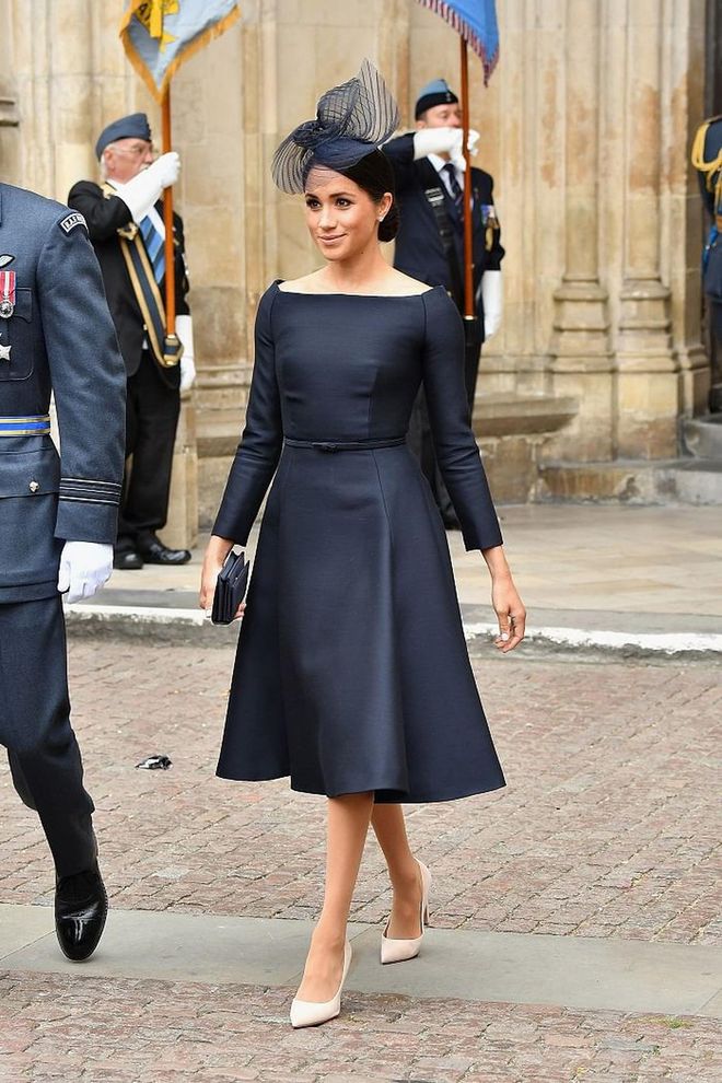 The Duchess of Sussex attends the centenary of the RAF in a bespoke Dior fit-and-flare navy dress with a boat neckline, reminiscent to her wedding gown. She wore a custom navy headpiece by Stephen Jones , a Dior satin clutch from their FW17 collection and nude pumps.  