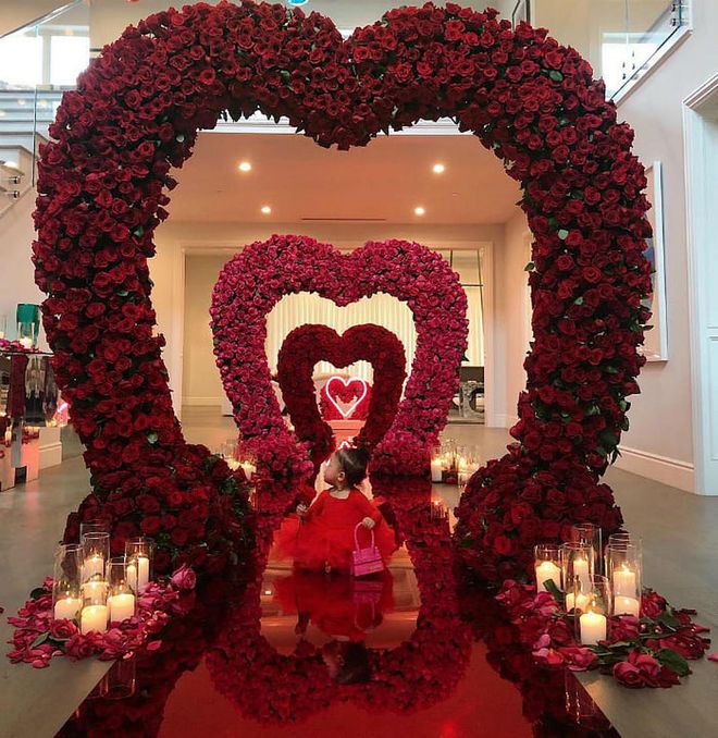 Kylie was in such amazement of the stunning rose-filled love tunnel boyfriend Travis Scott surprised her with on Valentine's Day Eve, that she had to share it again today. "Must be dreaming!! 🌹," she captioned the slideshow, which showed baby Stormi looking up at the heart-shaped archway. The second visual she shared was a day-time video of the set-up that features candles, a red glitter floor, and pink neon heart.