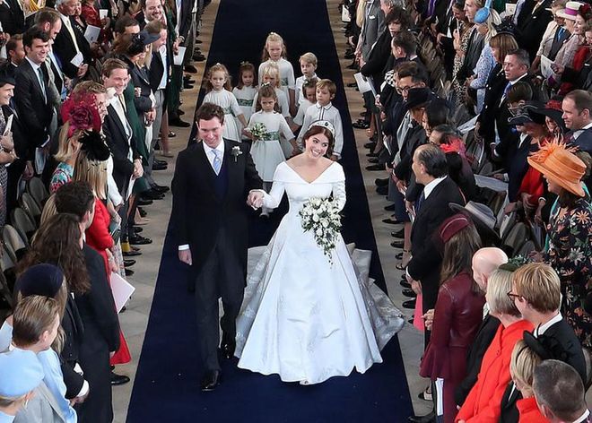 Princess Eugenie and Jack hold hands as they walk down the aisle as man and wife.