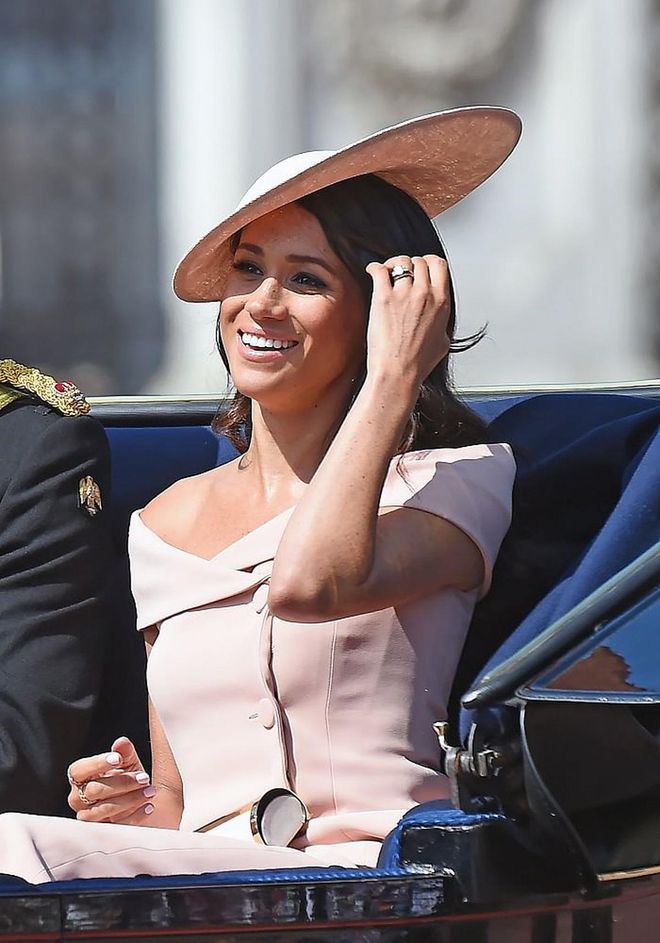 The Duchess Of Sussex's first Trooping The Colour appearance was in a sophisticated pastel pink off-shoulder top and midi-skirt by Carolina Herrera with a matching pink Philip Treacy natural straw slice hat. She accessorized simply with Carolina Herrera's Metropolitan Insignia clutch in white. 