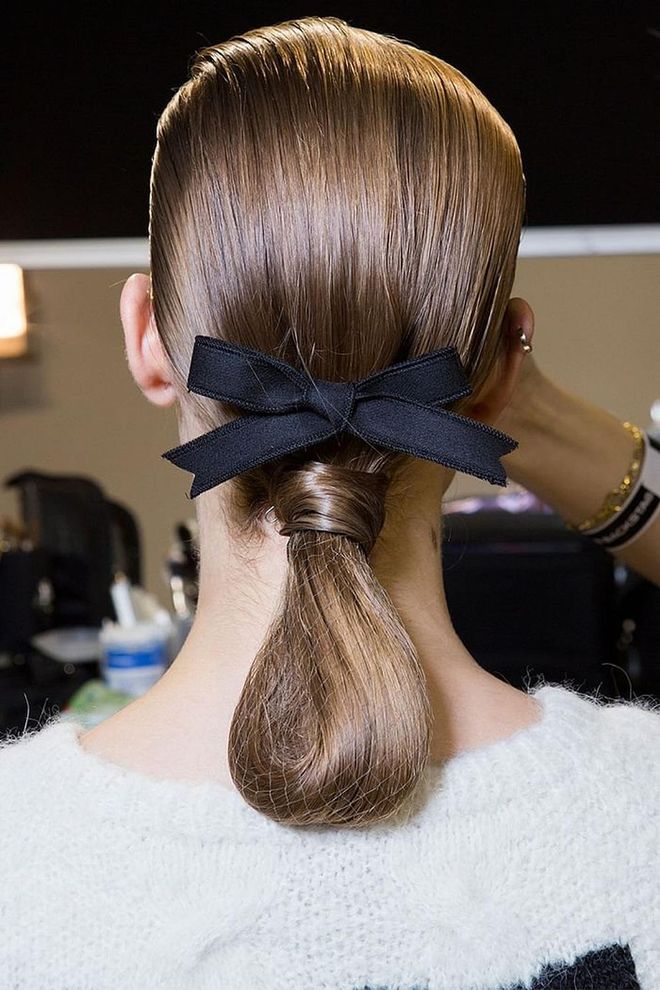 The hair at Rochas was all about refined, equestrian-inspired glamour. But hairstylist Paul Hanlon didn't want to simply pull it back into a bun. Instead, he parted the hair to the side, swept it back into a low ponytail, and then rolled the hair together "like tails of Dressage horses," notes WWD. A black bow—one of the biggest hair trends of the season so far—was placed just above the base.