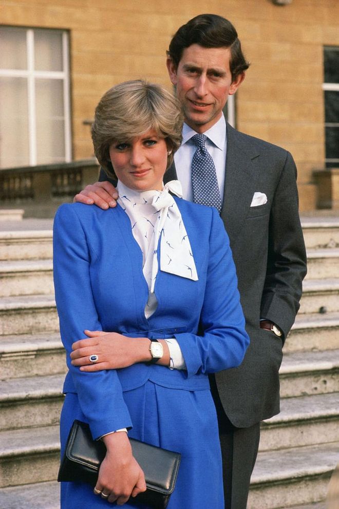 Lady Diana Spencer—later known as Diana, Princess of Wales—and Prince Charles pose outside Buckingham Palace to celebrate their engagement. The bride-to-be flaunts her ring, featuring an oval sapphire surrounded by blue diamonds.