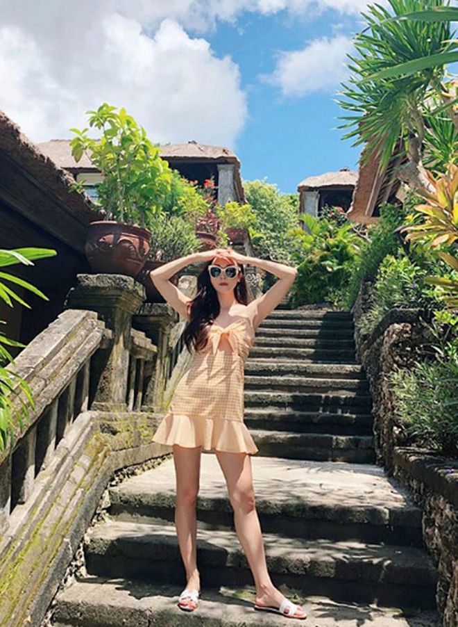 On a trip to Bali, Jessica styles a sunny gingham yellow dress with sleek Hermes slides while standing on the steps at the Four Seasons. 
Photo: Instagram