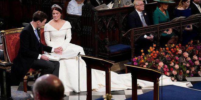 Brooksbank admires Princess Eugenie's jewelry as they sit during their service.