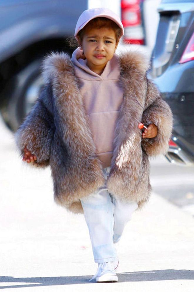 The toddler elevates her casual street style look of a pink sweatshirt, matching baseball cap and Chuck Taylors with a chic fur coat. Photo: AKM-GSI