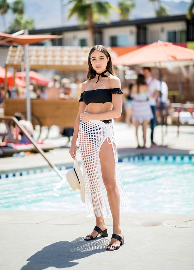 Olivia channels some poolside vibes with a black cropped off shoulder top, net skirt, sandals at the Revolve Pool Party in Palm Springs, California. Photo: Getty