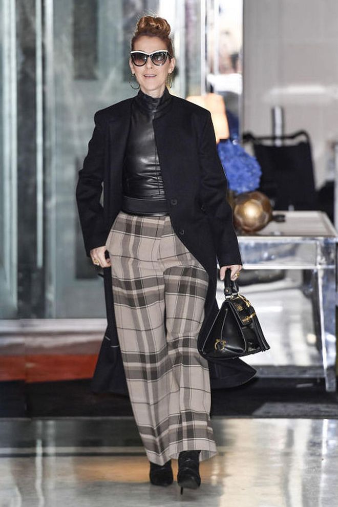 In a leather mock neck top, plaid wide-leg trousers, pointed-toe boots, a black trench coat, black handbag and oversized sunglasses.
Photo: Splash