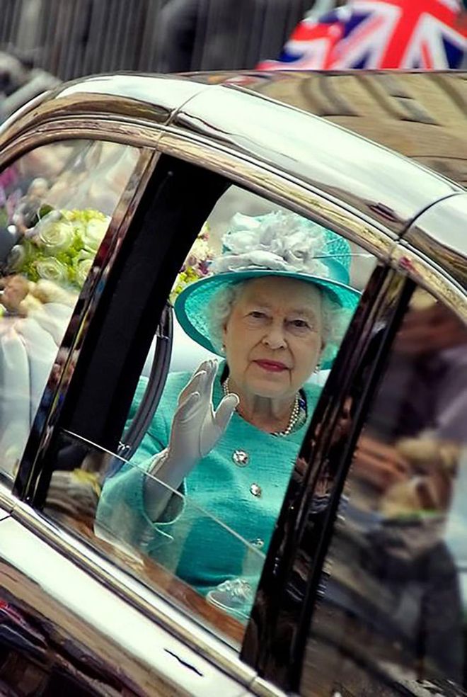 The monarch waves from a car while being driven through Stamford in Lincolnshire.