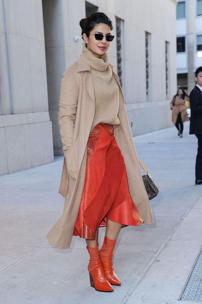 Chopra made a classic camel turtleneck and jacket combo pop by adding a red leather midi skirt and matching red ankle boots.

Photo: Getty