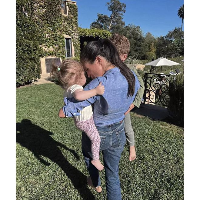 Meghan carrying her children in her arms at her and Harry’s Montecito, California home.