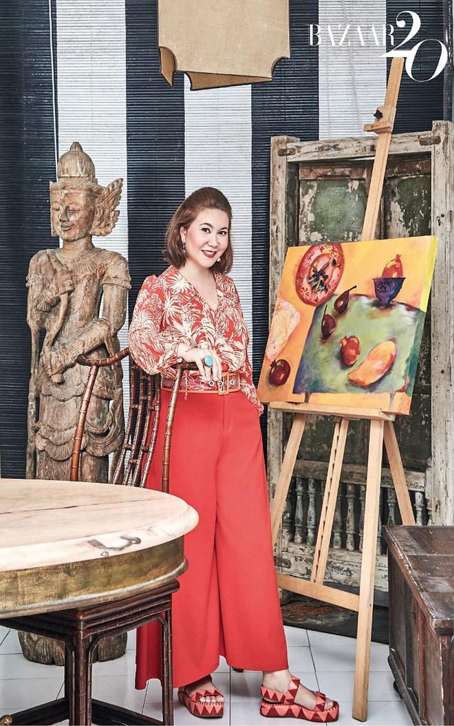 Desmazieres, wearing her own Rixo blouse, trousers, Maison Boinet belt, jewellery and Sergio Rossi shoes, standing by one of her own artworks in the dining corner of her patio, which is decorated
with an old Indian window and a Burmese statue.

(Photo: Phyllicia Wang)