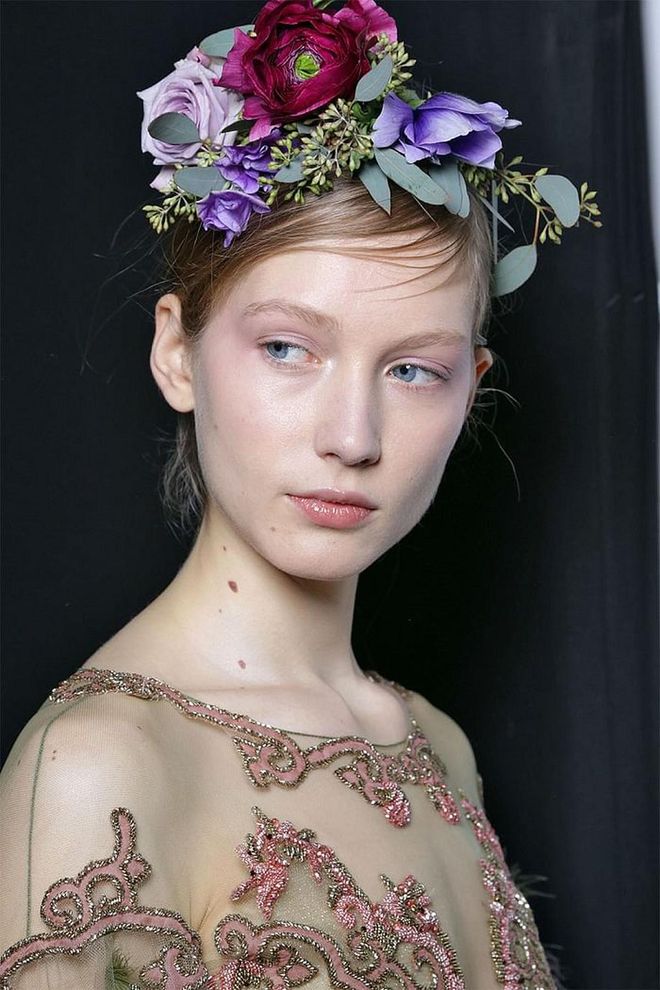 In the center of the hair room backstage at Marchesa was a table full of fresh-cut flowers, still wrapped in paper from the store. Though they could have been mistaken for a gift, the flowers were actually the starring hair accessory for a handful of lucky models. Hairstylists cut, sewed, and pinned the flowers along their head like a crown. The end result was nothing short of stunning.
