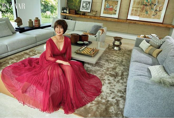 Goh-Rin looking resplendent in a Dior dress and necklace, perched on a couch in her living room.