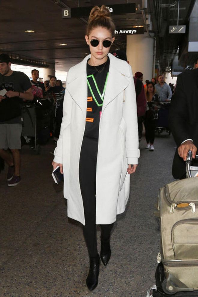 Gigi Hadid paired a graphic sweatshirt with jeans and a simple coat as she boarded a flight. Photo: Getty