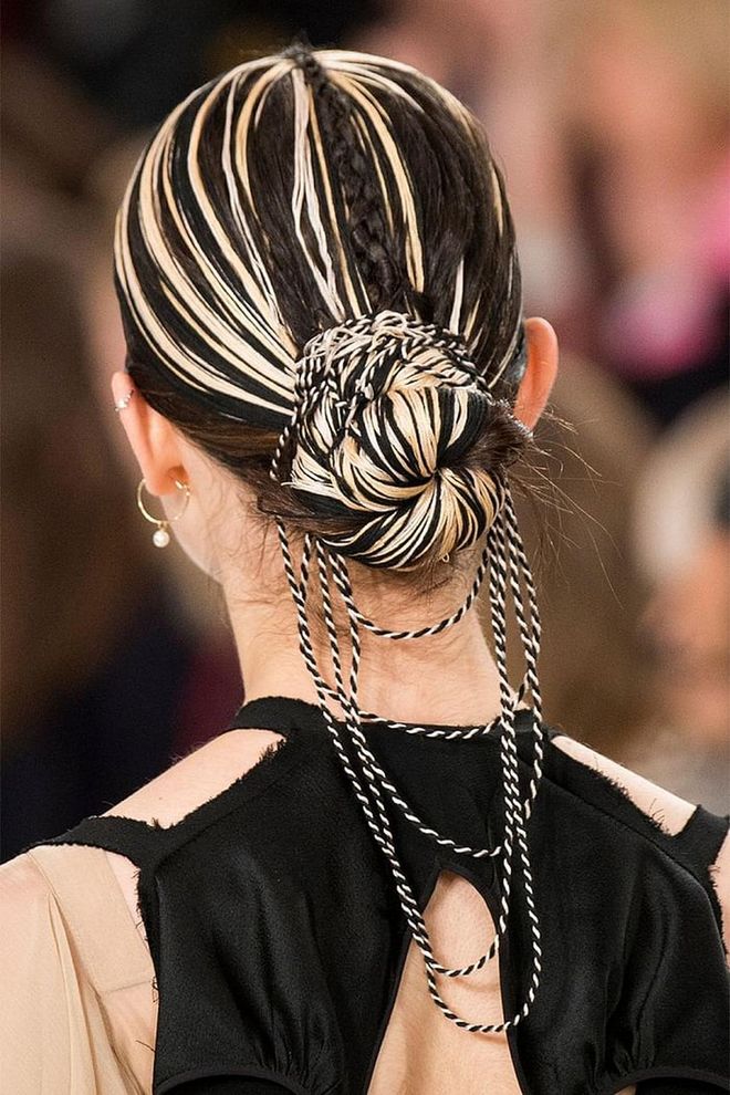 At Maison Martin Margiela, string theory took on a whole new meaning. Some models walked the runway with their hair looped into a multicolored chignon, and decorated with bits of string. 