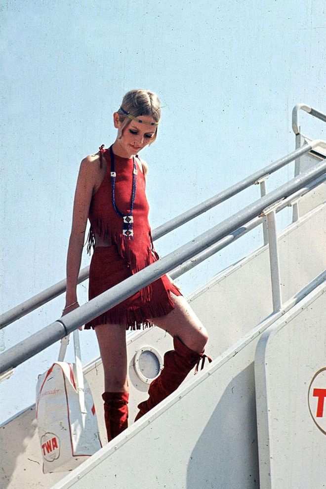 Twiggy is suede knee-high red boots, a matching fringe halter top and mini skirt while boarding a plane  in London. Photo: Getty 