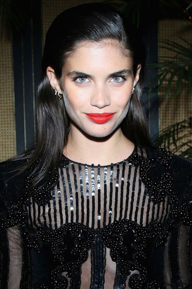 Sampaio goes for full-on glamour with slicked-back hair, a sequined Balmain dress, and a bright pop of red lipstick.
