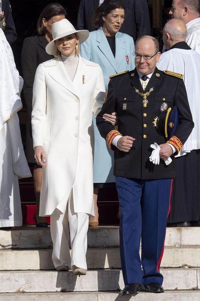 Princess Charlene, dressed elegantly in an all-white ensemble and hat, takes the arm of her husband during the holiday celebrations.

Photo: Getty