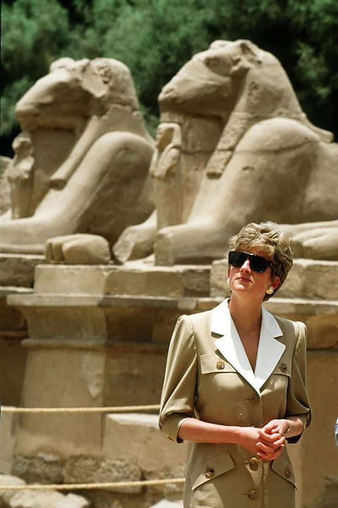In a Catherine Walker dress, sunglasses, and oversized earrings while visiting Karnak Temple in Luxor, Egypt.

