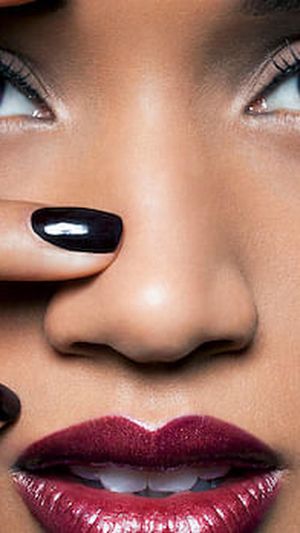 Young woman with red lips and black nail polish.