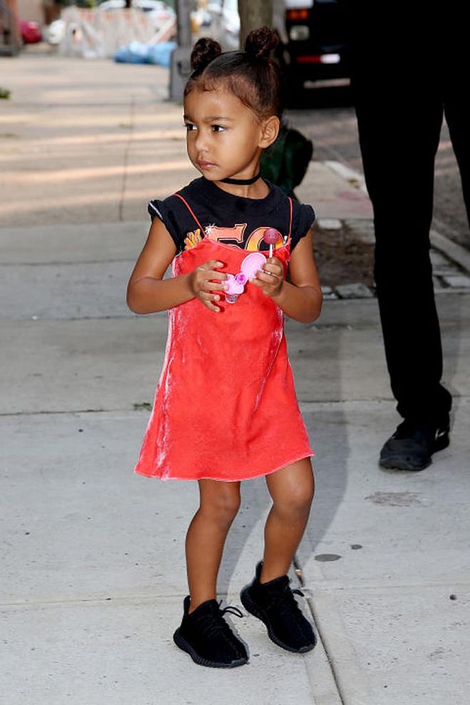 North went full '90s (again) in a red velvet slipdress layered over a black graphic tee, plus a skinny choker necklace and black baby Yeezys. Photo: Getty 
