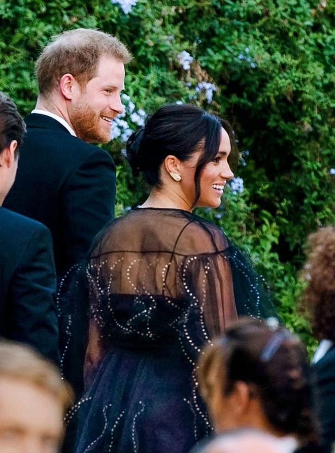 Prince Harry and the Duchess of Sussex were spotted arriving to the wedding of Misha Nonoo at Villa Aurelia in Rome. Meghan wore a sheer, embellished black Valentino dress and sparkling gold feather earrings.