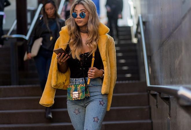 A guest wearing a yellow jacket, Furla bag. Photo: Getty 