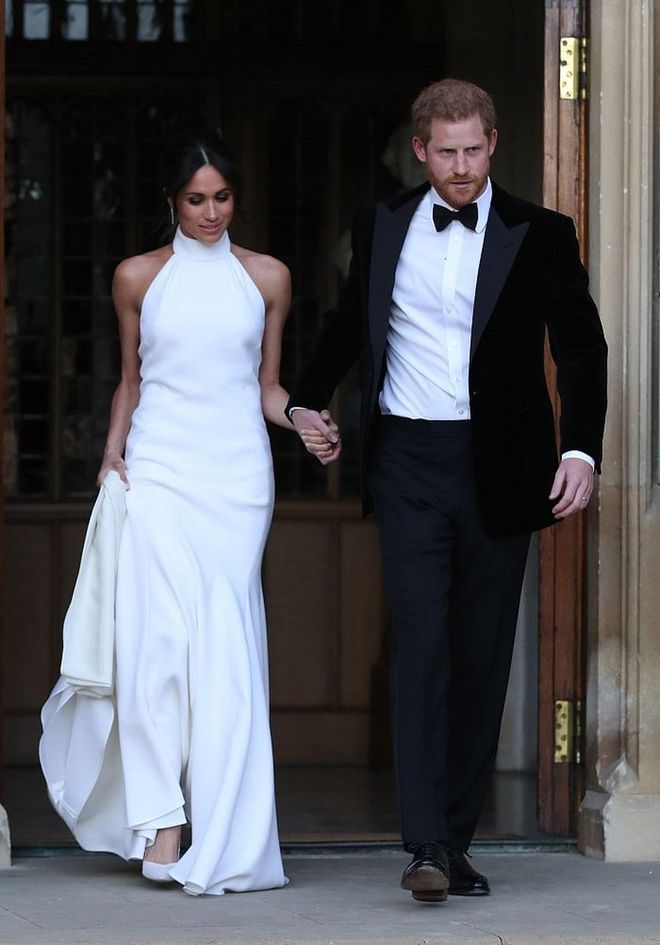 For the wedding reception, Meghan opted for a sleek white gown by Stella McCartney  with a halter neckline. Custom, of course! She matched the gown with satin pumps by Aquazurra, which had the soles painted baby blue and Princess Diana's cocktail ring. The earrings are from Cartier's Reflection de Cartier collection. 