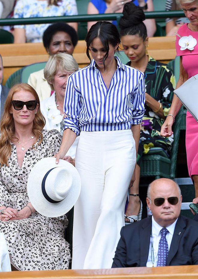 Meghan Markle wore a striped Ralph Lauren shirt with white palazzo pants to watch WImbledon. She also carried a hat and black handbag. Photo: Getty