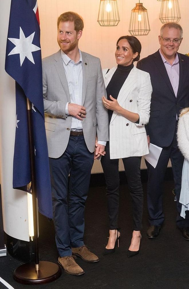 The Duchess of Sussex attended an Invictus Games reception in a white pin-striped L'Agence blazer over a black turtleneck bodysuit and black denim. Meghan opted to accessorize with a black and white Oroton 'Avalon' Crossbody Bag and Aquazzura 'Deneuve' Black Suede Bow Pumps. 