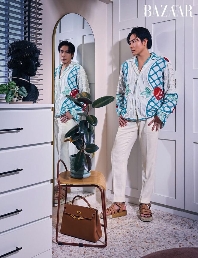 Hong in his walk-in-wardrobe, wearing a Bode shirt, Suit Supply trousers and Prada sandals, with a Hermès Kelly bag at his feet.