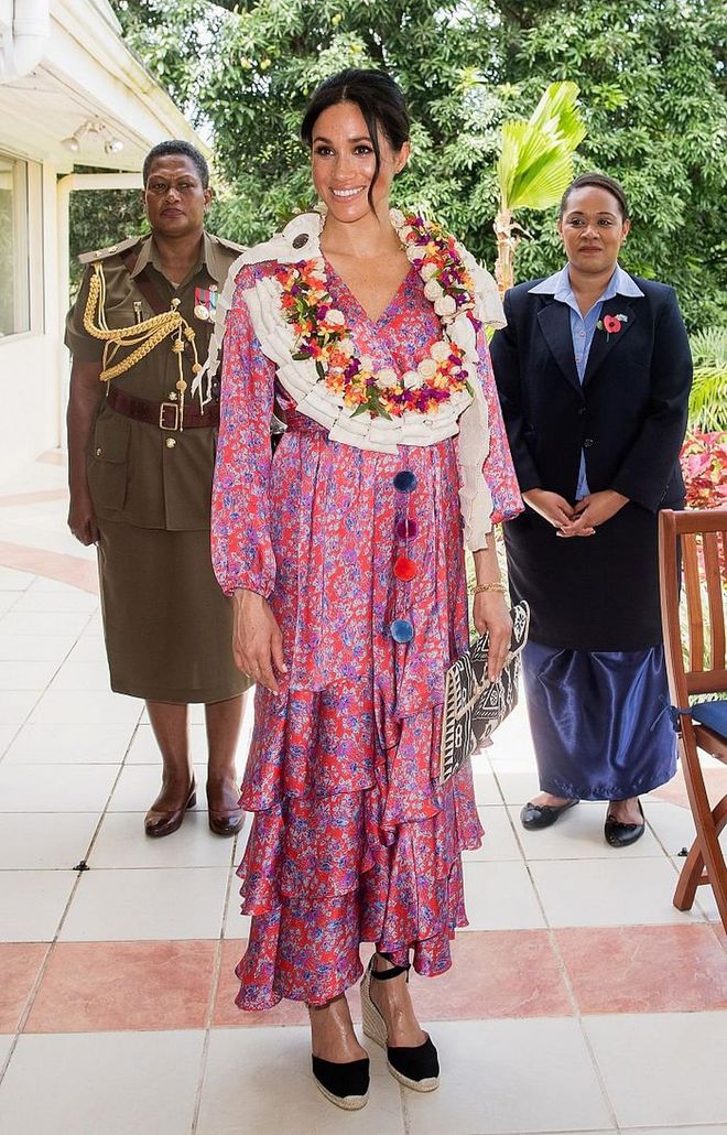 The Duchess of Sussex attends a morning tea reception at the British High Commissioner's Residence in a colourful Figue 'Frederica' Printed Ruffle Dress, carrying a black and white printed clutch purchased at the Suva Market in Fiji. 